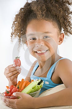 Young girl eating bowl of vegetables in living roo
