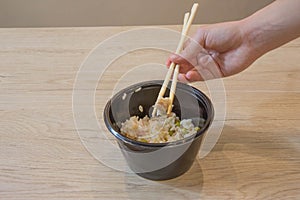 Young girl eating in a Chinese food, they eating with chopsticks, close-up on hands and food