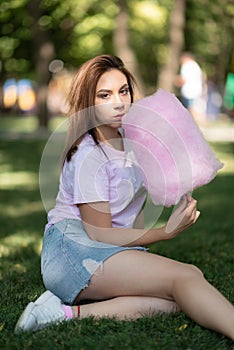Young girl eating cotton candy in the park