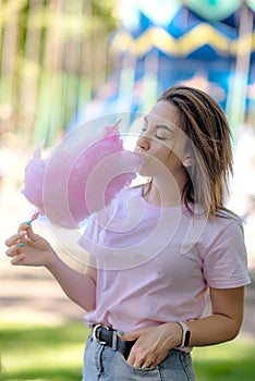 Young girl eating cotton candy in the park
