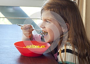 Young girl eating macaroni and cheese