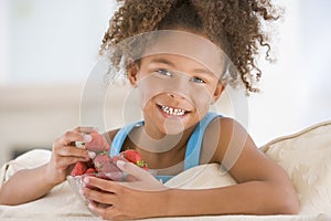 Young girl eating strawberries in living room