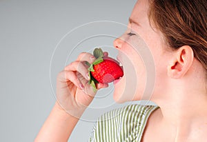 Young girl eating strawberry