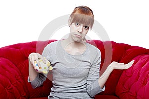 Young girl with empty piggybank on red sofa