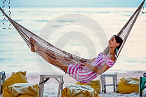 Young girl enjoying the evening lying in a hammock on the coast