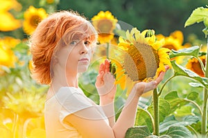 young girl enjoying nature on the field of sunflowers at sunset, portrait of the beautiful redheaded woman girl with a sunflowers