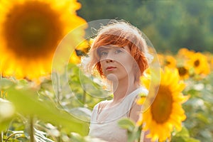 young girl enjoying nature on the field of sunflowers at sunset, portrait of the beautiful redheaded woman girl with a sunflowers
