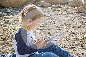 Young girl enjoying a peaceful moment by the lake while immersed in a captivating book