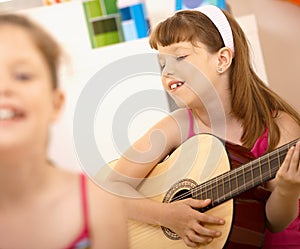 Young girl enjoying playing guitar