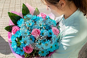 Young girl enjoys the flavor of bouquet of blue and rose flowers. Present for Birthday, Women`s day or Valentine`s day