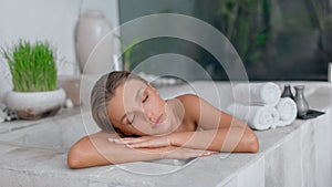 Young girl enjoys spa treatments in the bathroom with flowers