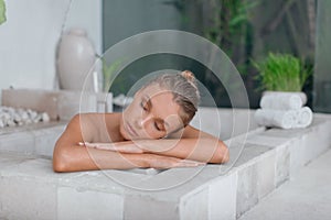 Young girl enjoys spa treatments in the bathroom with flowers