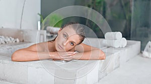 Young girl enjoys spa treatments in the bathroom with flowers