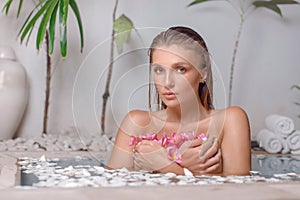 Young girl enjoys spa treatments in the bathroom with flowers