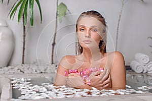 Young girl enjoys spa treatments in the bathroom with flowers