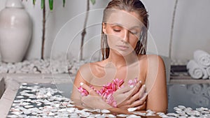 Young girl enjoys spa treatments in the bathroom with flowers