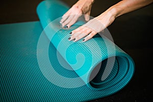 Young girl enrolling blue yoga mat after practicing workout and crossfit