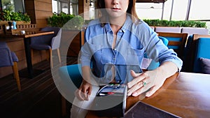 Young girl entering pin code on magnetic card reader at restaurant.