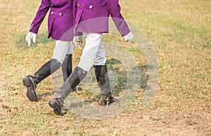 Young girl equestrians in professional apparel dressage purple jacket walking in th