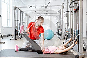 Young girl exercising with trainer at the rehabilitaion gym