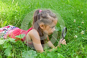 Young girl exploring nature looking at magnifying glass