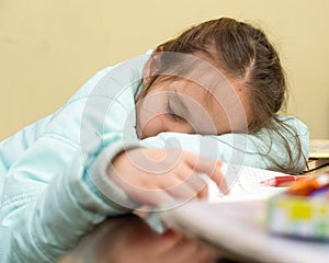 Young girl falling asleep doing homework