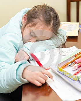 Young girl falling asleep doing homework