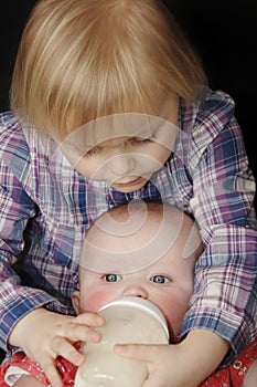 Young girl feeding baby sister