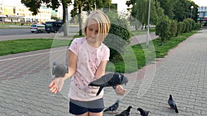Young girl feeding pigeons sunflower seeds with hands on the street in the city
