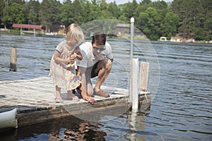 Young girl feeds fish from a dock in Minnesota with her father