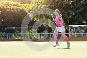 Young girl field hockey player running on pitch