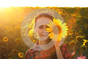 A young girl in a field of sunflowers at sunset