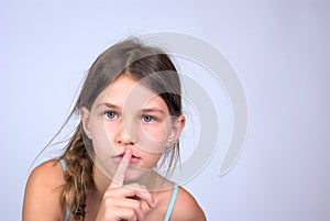 Young girl with finger on lips shushing photo