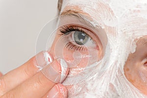 Young girl fingers applying face mask moisturizer photo