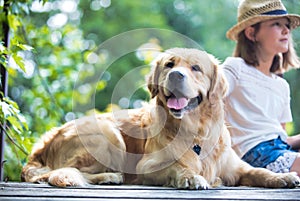 Young girl fishing while sitting with dog on pier