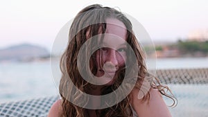 Young girl flirting shrugs Loose curly wet hair making eyes