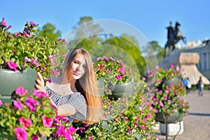 A young girl at the flower beds on the background of the monument bronze Horseman in Saint-Petersburg
