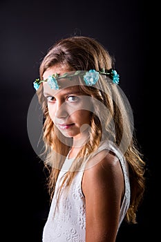 Young girl with flower tiara and sober look on black background photo