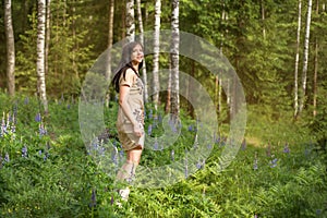 Young girl in a forest park whirl dances among flowers and birch trees