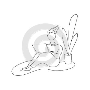 Young girl freelancer works at home in a cozy room. Sits on the floor, on his lap a laptop