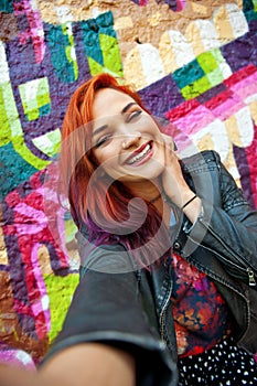 Young girl in front of graffiti making selfie