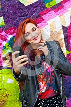 Young girl in front of graffiti making selfie