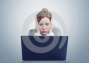 Young girl in front of a laptop clutched her head.