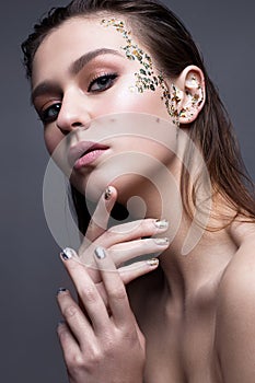 A young girl with a gentle classical make-up and loose hair. Beautiful model with creative art make-up and manicure from foil.