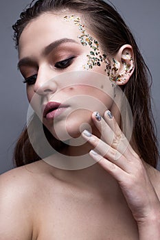A young girl with a gentle classical make-up and loose hair. Beautiful model with creative art make-up and manicure from foil.