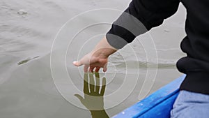 Young girl gently touching water on lake. Woman leads palm on green water. Close up of woman hand touches water in park. Woman han