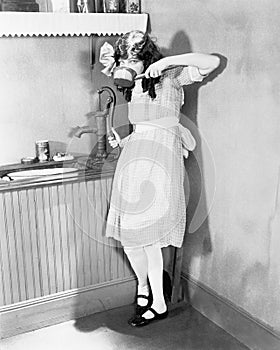 Young girl gets a sip of pump water in the kitchen
