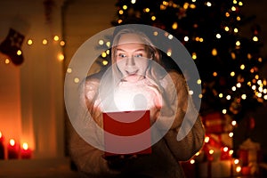 Girl with gift box near christmas tree