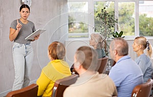Young girl giving lecture to group of older adults