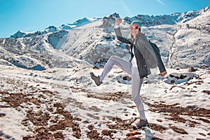 A young girl in glasses dances on the snow. Mountain peaks in the winter season